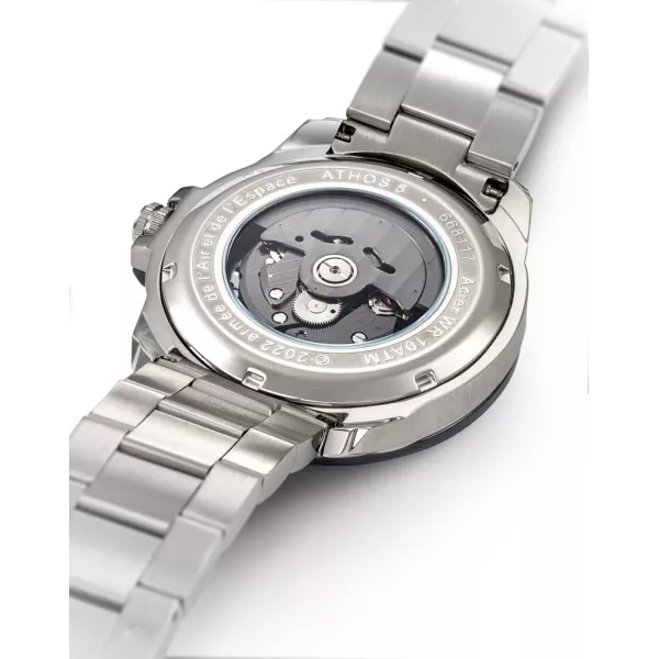 Dos de la montre laissant apparaitre le mécanisme de la montre, détails tricolores brodés sur le bracelet.