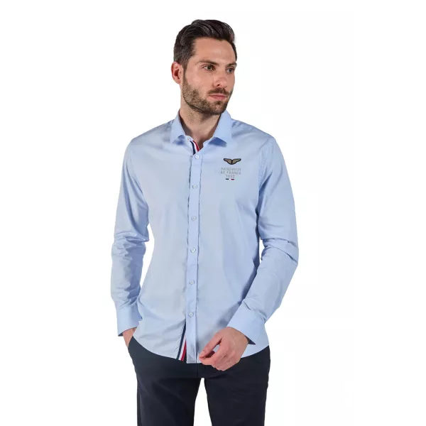 Chemise bleu ciel avec liseré tricolore au niveau des boutons.