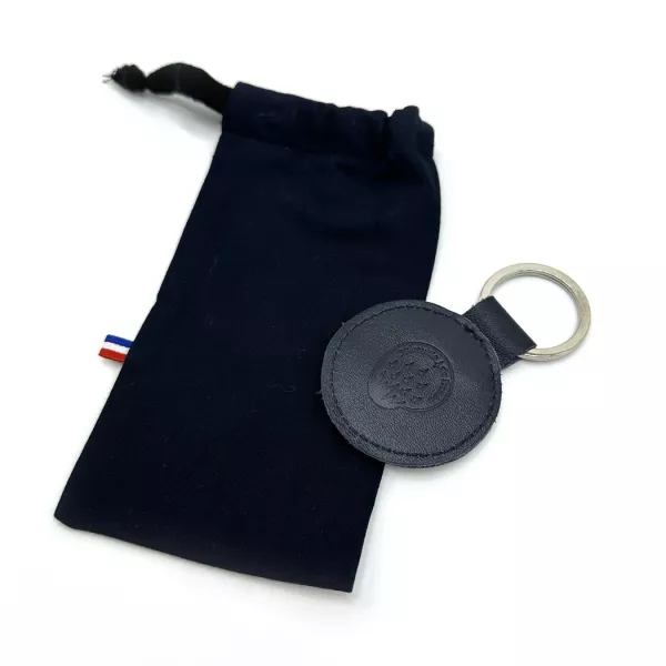 Porte-clé présenté dans un petit pochon en tissu bleu marine.