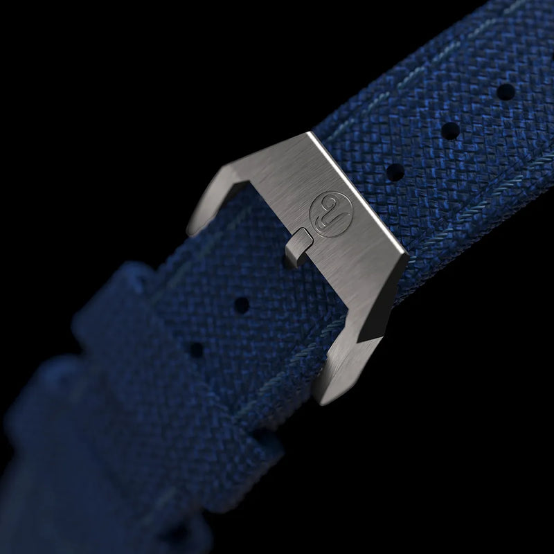 Boucle argentée du bracelet en tissu bleu, gravée avec le logo Yema.
